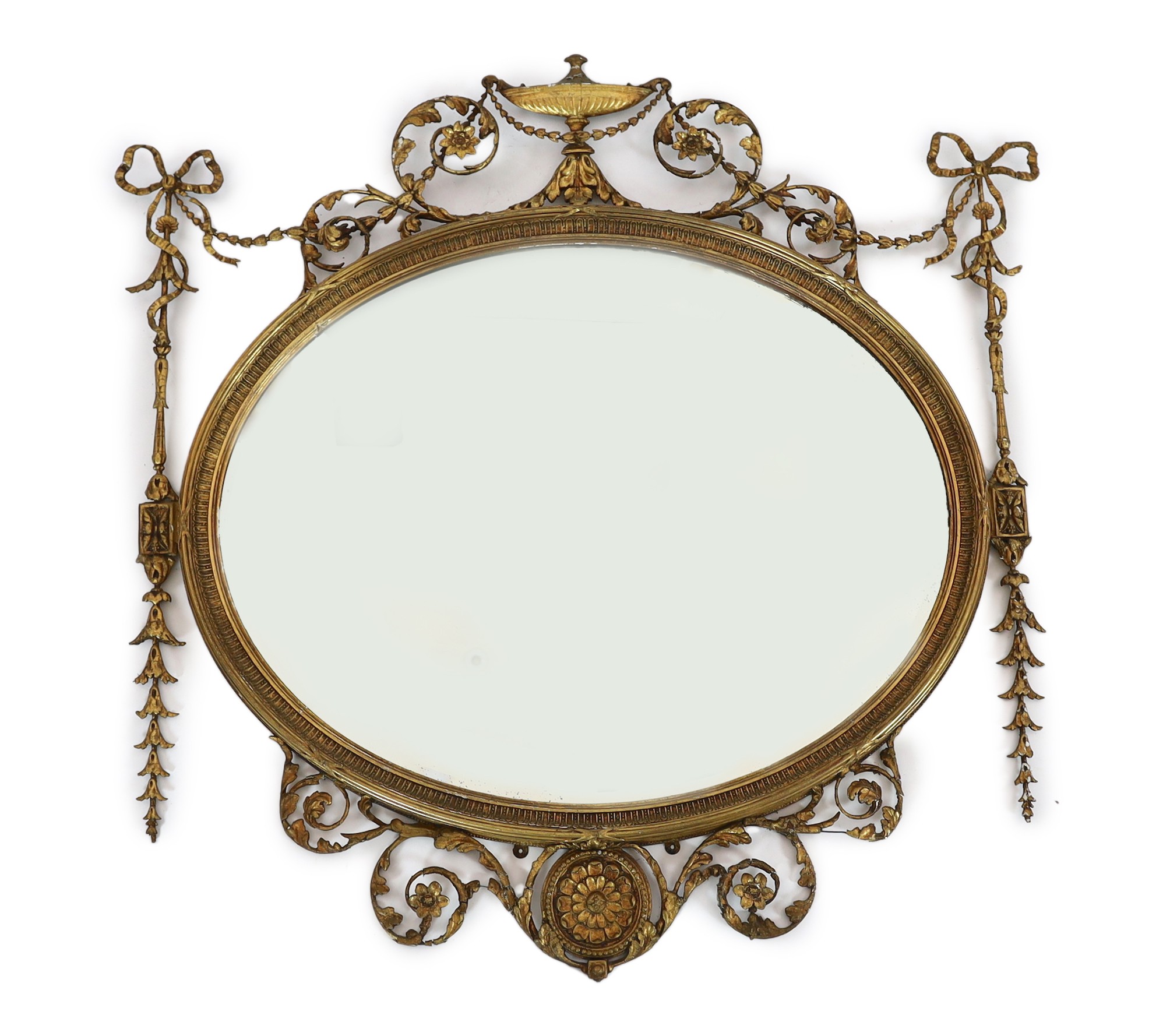 A late Victorian Adam Revival oval wall mirror, with urn, foliate scroll, ribbon and harebell motifs, and bevelled glass plate, width 119cm, height 118cm